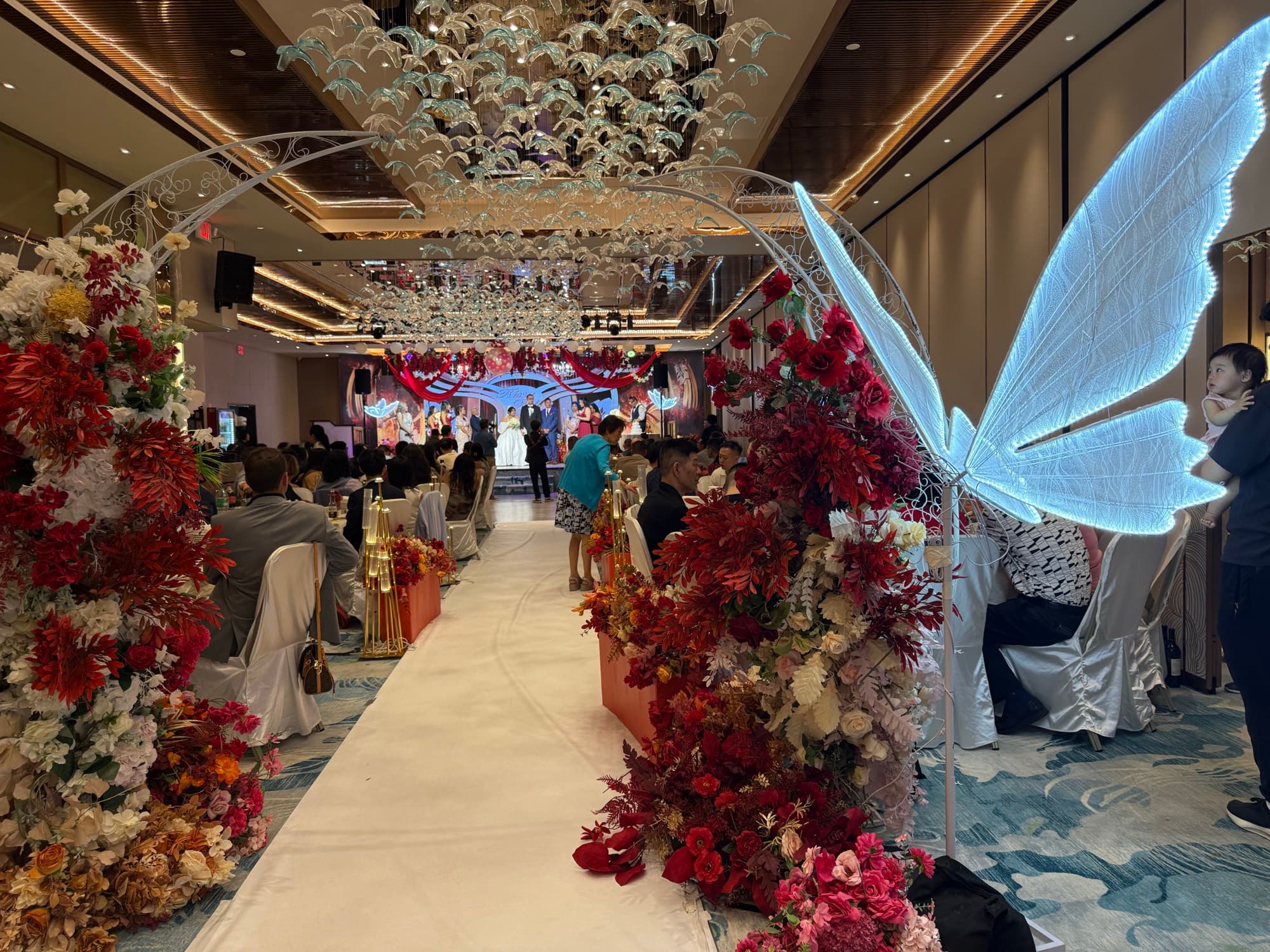 Grand floral aisle beneath the butterfly light installation