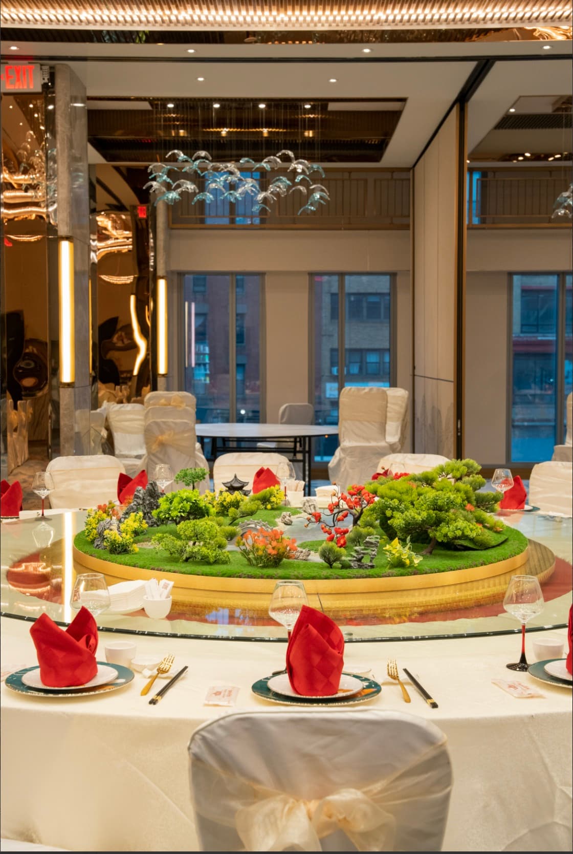 A round banquet table with an ornate green garden-scape centerpiece