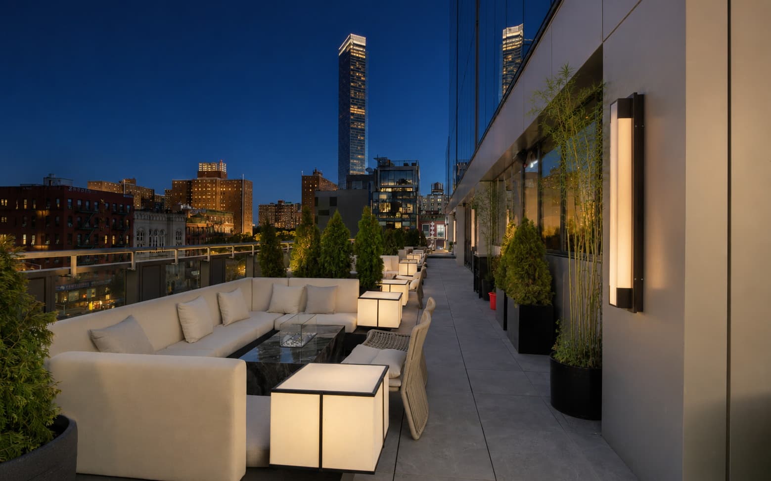 Terrace banquette and fire table at blue hour, with the Manhattan skyline behind